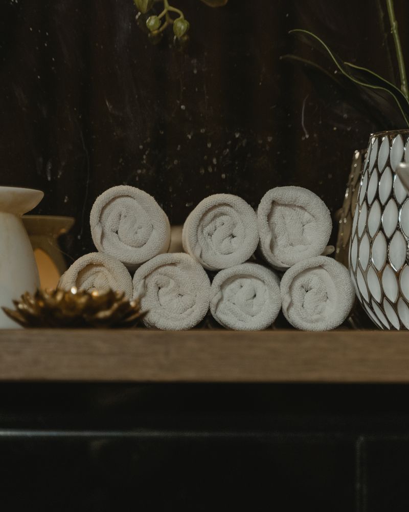 Detail salonu SALON NICE – svinuté ručníky a svíčka